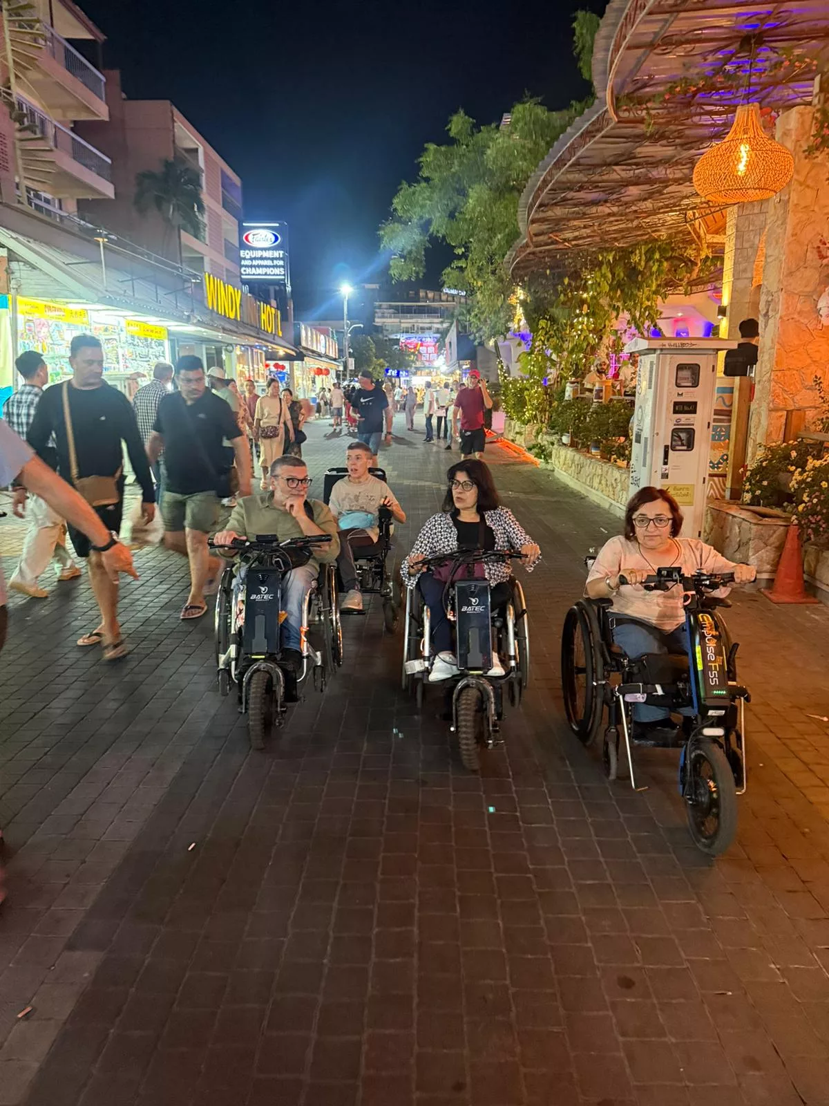A group of wheelchair users with motorized adaption cruise Thailand at night.